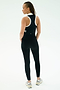 A person faces away, wearing the SPLITS59 Amber Airweight High Waist 7/8 Black/White leggings with a matching sleeveless top and white sneakers, set against a plain light background.