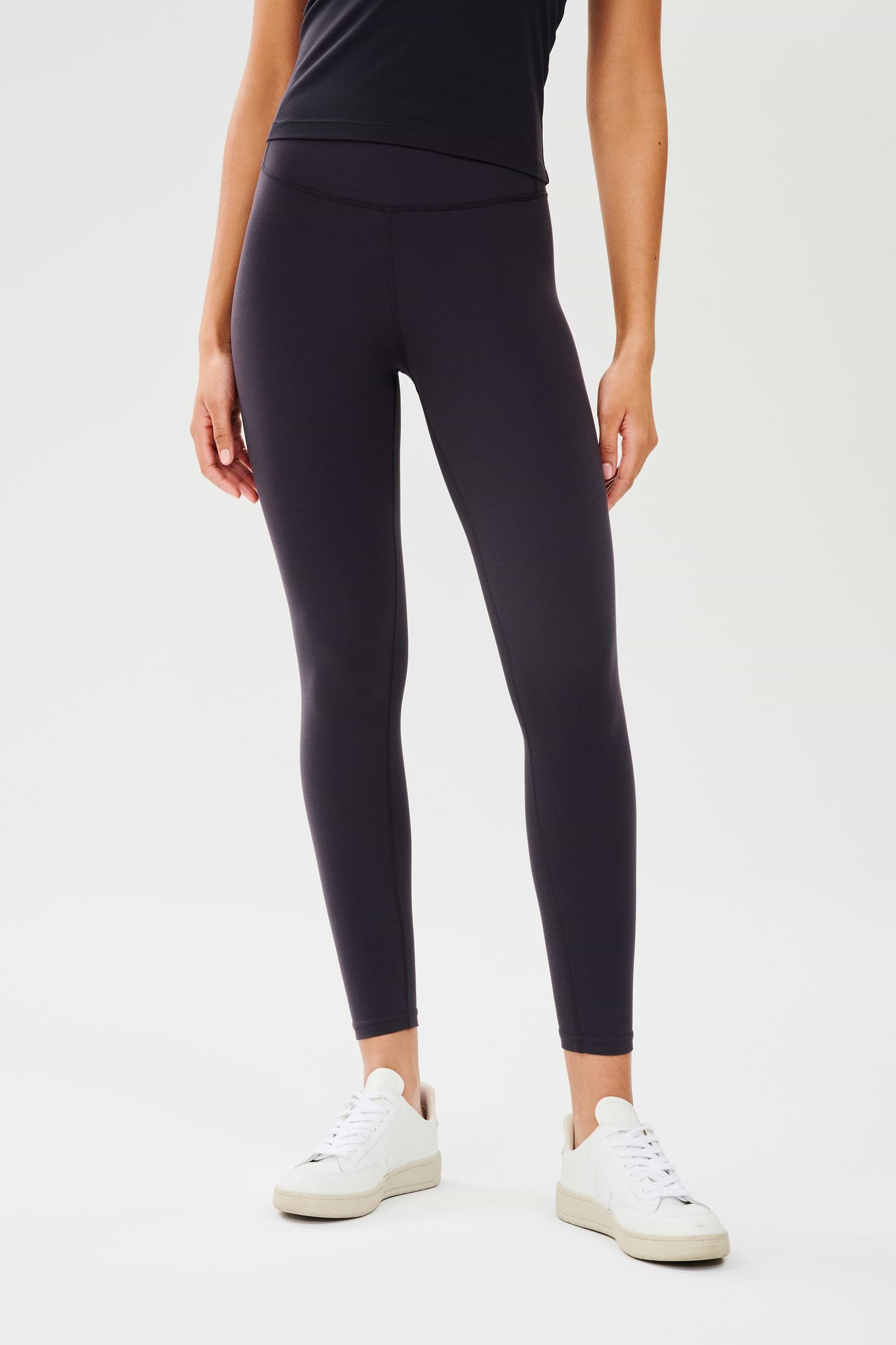 Front view of girl wearing highwasited black leggings with  white shoes