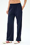 A person wearing SPLITS59 Maxie Rigor Track Pant in Indigo/White with white sneakers featuring red stripes stands against a plain background.