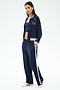A woman stands against a plain light background wearing the SPLITS59 Hayes Varsity Rigor Jacket in indigo, paired with matching pants and white sneakers with red accents.