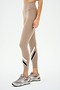 A person stands against a plain background in SPLITS59 Chevron Airweight High Waist 7/8 leggings in Latte/Indigo and gray sneakers. The leggings' ultra-luxe fabric offers both elegance and comfort.