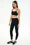 A woman stands against a white background wearing the SPLITS59 Elliah Airweight Double Layer Bra in Black/White.