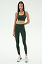 A woman stands against a plain background wearing the SPLITS59 Margot Rigor Legging in Military/Blush and a matching dark green sports bra, paired with white sneakers.