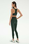 A woman faces away, wearing the SPLITS59 Lexi Rigor Bra in Military/Blush with matching leggings and white sneakers, set against a plain white background.