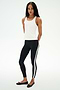 Person wearing the SPLITS59 Mel Airweight Lite Tank in white, perfect for hot yoga or Pilates, paired with black leggings with a white side stripe and black flats against a white background.