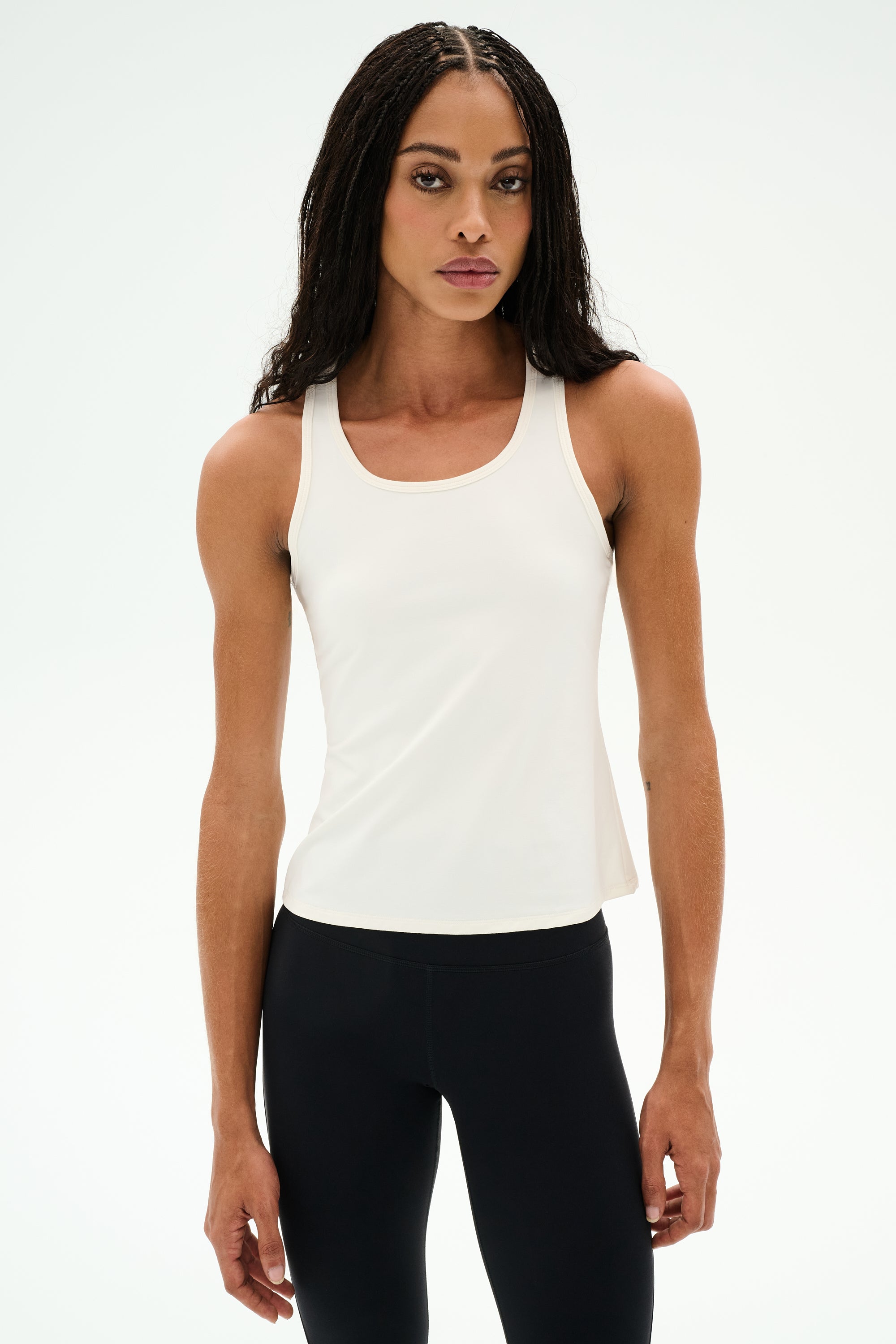 Woman wearing the SPLITS59 Mel Airweight Lite Tank in white, standing against a plain white background—ideal for Pilates or hot yoga.