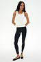 A woman poses against a white background in the SPLITS59 Mel Airweight Lite Tank - White, paired with black side-stripe leggings and black ballet flats—ideal for Pilates or hot yoga.