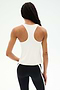 A person with long braided hair stands with their back to the camera in a SPLITS59 Mel Airweight Lite Tank - White, styled perfectly for Pilates or hot yoga, against a plain background.