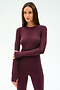 A woman poses against a plain background, wearing the SPLITS59 Louise Rib Long Sleeve in Dark Cherry with matching spandex leggings, her arms crossed in front of her.