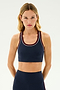 A woman with long blonde hair is wearing an SPLITS59 Robbie Airweight Bra in Indigo/Dark Cherry and matching athletic leggings against a neutral background, perfect for hot yoga sessions.