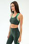 A woman wears the SPLITS59 Robbie Airweight Bra in Military/Spearmint, paired with matching high-waisted leggings, standing against a plain white background.