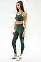 A woman in the SPLITS59 Robbie Airweight Bra - Military/Spearmint stands in profile against a white background, wearing matching green-striped leggings and white sneakers with green stripes.