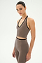 A woman wearing the SPLITS59 Rory Airweight Halter Bralette in Lentil/Black, featuring soft stretch material, stands against a plain white background.