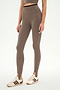 Wearing SPLITS59′s River Dual Waist Airweight Stirrup leggings in Lentil/Black, this individual stands against a plain white background.