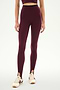 A person wears the SPLITS59 River Dual Waist Airweight Stirrup leggings in Dark Cherry/Black, paired with a matching crop top and white sneakers featuring burgundy stripes, standing against a plain background.