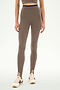 A person is wearing the SPLITS59 River Dual Waist Airweight Stirrup leggings in Lentil/Black, featuring a high-waisted design with stirrups and crafted from a stretchy nylon-spandex blend ideal for athletic wear. The look is paired with a matching crop top and cream sneakers with brown stripes, set against a plain white background.