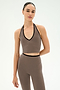 A person stands against a plain white background wearing the SPLITS59 Rory Airweight Halter Bralette in Lentil/Black, paired with matching high-waisted leggings, both crafted from stretchy nylon-spandex athletic fabric.