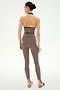 A person stands against a plain background, facing away from the camera, wearing the SPLITS59 Rory Airweight Halter Bralette in Lentil/Black paired with matching stretch leggings and sneakers.