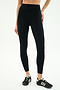 Wearing SPLITS59 Layla Airweight High Waist 7/8 in Black/Lentil and black sneakers with white stripes, standing against a light background—ideal for hot yoga or any workout.