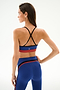 A woman wearing a Scottie Airweight Bra in Cobalt/Indigo and matching high-waisted leggings with a black crisscross back.