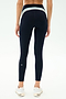 A person is shown from the back in SPLITS59 Emerson Airweight High Waist leggings in Indigo/Dove Grey with white sneakers, against a plain background—ideal attire for Pilates or hot yoga sessions.