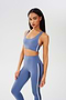 Side view of girl wearing light blue sports bra with thin black and white stripes down the side and light blue leggings