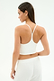 A woman models the SPLITS59 Airweight Crop - White, a white cropped tank with thin straps, paired with white pants and shown from the back against a plain background—ideal for hot yoga or casual wear.