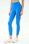 A person stands against a plain light background wearing SPLITS59 Dual High Waist Airweight 7/8 leggings in Classic Blue/Ray and white athletic shoes—an ideal outfit for hot yoga.