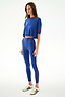 Woman wears the SPLITS59 Djuna Oversized Crop Jersey Tee - Cobalt/Terracotta with high-waisted leggings and white sneakers, standing against a plain white background.