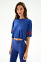 A woman wears the SPLITS59 Djuna Oversized Crop Jersey Tee - Cobalt/Terracotta with matching high-waisted leggings, standing against a plain light background.