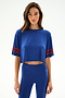 A woman wears the SPLITS59 Djuna Oversized Crop Jersey Tee - Cobalt/Terracotta, paired with matching high-waisted leggings, against a plain white background.