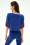 A woman faces away in the Djuna Oversized Crop Jersey Tee - Cobalt/Terracotta by SPLITS59, paired with high-waisted spandex leggings, against a plain white background.