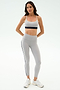 A woman poses against a plain background in the SPLITS59 Emerson Airweight Bra in Dove Grey/Indigo, paired with matching leggings and white sneakers—perfect for Pilates or hot yoga.