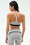 A woman stands with her back to the camera, wearing the SPLITS59 Emerson Airweight Bra in Dove Grey/Indigo and matching high-waisted leggings, perfect for hot yoga or Pilates.