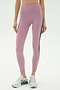 A person wears SPLITS59 Margot Rigor Legging in Blush/Military—mauve leggings with a dark green side stripe—paired with white sneakers, standing against a plain white background.