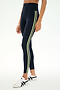 Wearing the SPLITS59 Ella High Waist Airweight 7/8 leggings in Indigo/Limeade, featuring two light green side stripes, paired with white sneakers and standing against a plain background.