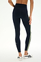 A person wearing SPLITS59 Ella High Waist Airweight 7/8 leggings in Indigo/Limeade, paired with white sneakers, stands against a white background.