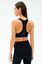 A woman is seen from behind wearing the SPLITS59 Mia Rigor Bra in black, paired with black leggings featuring white side stripes, perfect for gym sessions and set against a plain light background.