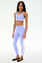 A person faces forward in a SPLITS59 Miles Rigor Bra - Purple Haze/White with matching leggings featuring white stripes and black ballet flats, set against a plain white background.