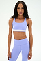 A woman wearing a SPLITS59 Miles Rigor Bra in Purple Haze/White with matching leggings stands facing forward against a plain white background.