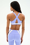 A woman, seen from the back against a plain background, wears SPLITS59’s Miles Rigor Bra in Purple Haze/White with crisscross straps and matching high-waisted leggings.