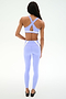 A person faces away, wearing the SPLITS59 Miles Rigor Bra in Purple Haze/White with crisscross straps and high-waisted leggings, set against a plain white background.