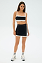 Sporting SPLITS59's Monah Rigor Bra in black/white, the person stands against a white backdrop in sneakers and striped socks—ideal for retro vibes or a gym workout.