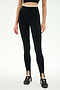 A woman stands against a plain white background wearing the SPLITS59 River Dual Waist Airweight Stirrup leggings in Black/Creme, crafted from a stretchy nylon spandex athletic fabric, paired with black sneakers. Her face is not visible.