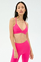A woman stands facing forward, wearing the SPLITS59 Theo Rigor Bra in Berry, paired with matching leggings, against a plain light background.
