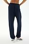 A person wearing the SPLITS59 Andie Oversized Fleece Sweatpant in Indigo and white sneakers stands with their back to the camera against a white background, ready for cool weather workouts in this comfy Los Angeles-made style.