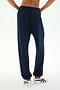 A person wearing the SPLITS59 Andie Oversized Fleece Sweatpant in Indigo and white sneakers stands with their back to the camera against a white background, ready for cool weather workouts in this comfy Los Angeles-made style.