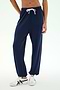A person wearing the SPLITS59 Andie Oversized Fleece Sweatpant in Indigo and white sneakers stands against a plain light background—perfect for cool weather workouts.