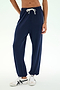A person wearing the SPLITS59 Andie Oversized Fleece Sweatpant in Indigo and white sneakers stands against a plain light background—perfect for cool weather workouts.