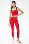 A woman wears the SPLITS59 Easton Rigor High Waist 7/8 leggings in Pirate Red/Indigo, featuring compressive fabric, paired with white and red Adidas sneakers, standing against a plain white background.